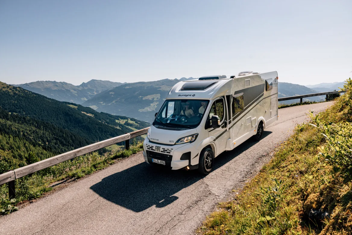 Wohnmobil reisen in den Alpen – Fiat Sunlight Camper auf Bergstraße mit Panoramablick